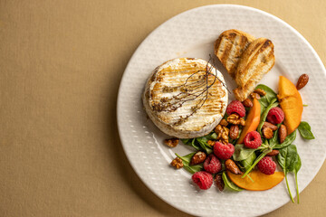 Baked camembert with caramelized nuts, spinach, raspberries and persimmons
