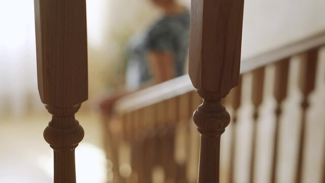 The girl goes down the stairs in the house, holding on to the handrails