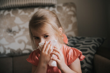 Toddler girl blowing her nose with a tissue