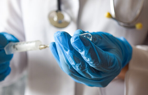 Ampoule and syringe in the hands of a doctor in blue gloves. Medicine, healthcare concept. Vaccination.