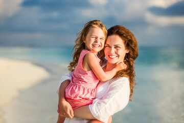 Fototapeta na wymiar Portrait of happy mother and little daughter on sunny beach on Maldives at summer vacation