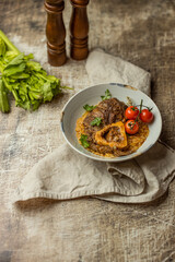 Osso buco traditional italian meat dish served with herbs and tomatoes