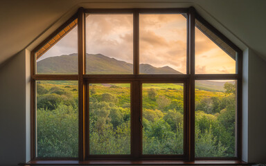 View through the wooden window on beautiful, dramatic sunrise over Carrauntoohil mountain and MacGillycuddys Reeks mountains, Ring of Kerry, Ireland