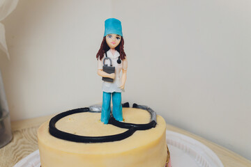 Nurses graduation cake with pink marshmallow fondant and edible cake toppers.