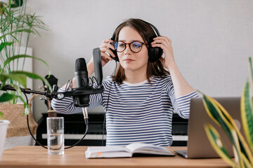 the stylish and educated caucasian woman records podcasts in a recording studio or in her home. the...
