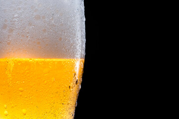 Half beer glass with beer and foam on a black background. Space for text and logo.