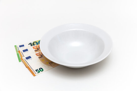 Money under an empty plate, euros on a white background. Hunger. There is money but no food