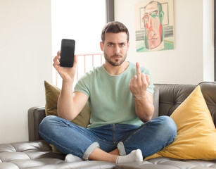 handsome man feeling angry, annoyed, rebellious and aggressive, flipping the middle finger,...