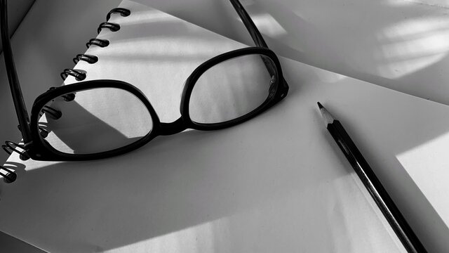 Eyeglass And Pencil On Paper Notebook In Black White Color Tone Image.