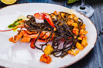 Squid ink tagliolini with lobster on white plate