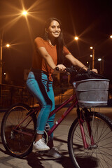 Fototapeta na wymiar hermosa Mujer joven maneja feliz en bicicleta por un parque por la ciudad. Modelo ciclista en mascarilla 
