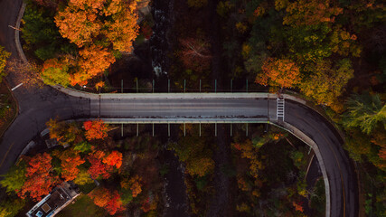 Aerial of Stewart Avenue Deck Truss Bridge over Canyon & Waterfall - Peak Autumn Colors - Ithaca, New York