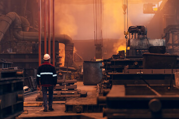 Worker inside Steel metallurgical factory or foundry workshop interior, heavy industry concept.