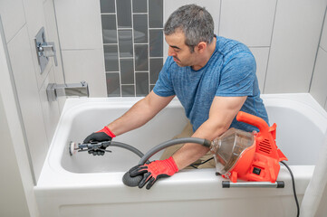 Plumber unclogging a bathtub drain