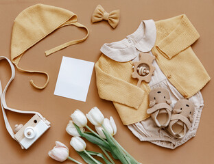 Baby clothes on brown background. Fashion baby outfit with tulips and booties. Top view, flat lay