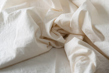 various folds of an ivory or warm white cotton fabric with directional light emphasizing natural...