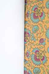 orange and blue florals scrapbooking paper bound together - with lens or camera focus on the crease between the pattern and the blank sections 