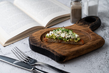 A single avocado toast with feta cheese and sprouts on a wooden board, close up, ad, advertisement, lite morning shot
