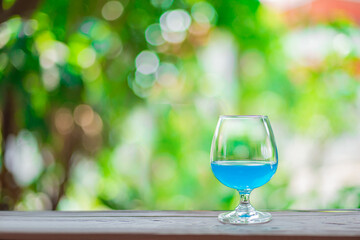 A glass with blue water placed on a wooden bar