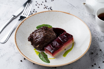 Soft cheeks with special cheese beetroot sauce and mashed potato on white stone table in a wide restaurant bowl, magazine photo