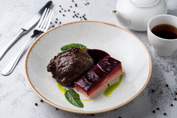 Soft cheeks with special cheese beetroot sauce and mashed potato on white stone table in a wide restaurant bowl, magazine photo