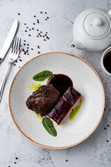 Slow cooked, stewed beef cheeks, directly above view on white stone table, with knife and fork around