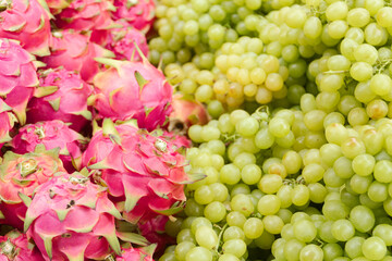 Fresh dragon fruit and green grapes in a greengrocer's shop