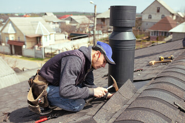 a professional master roofer with hammer repairs the roof. Repair Asphalt Shingles or Bitumen Tiles...