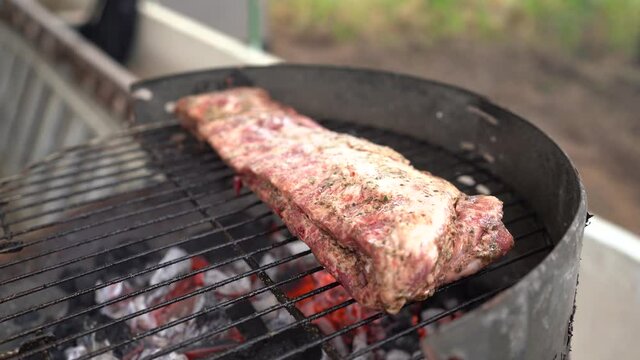 Carne variada sobre barbacoa en el exterior con amigos de fondo