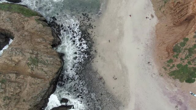 Aerial Of People By Famous Keyhole Arch At Pfeiffer Beach, Drone Descending Over Natural Landmark Splashing Waves - Big Sur, California