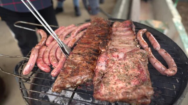 Carne variada sobre barbacoa en el exterior con amigos de fondo
