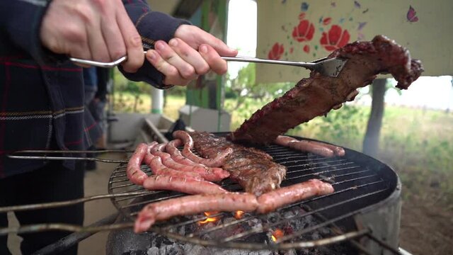 Carne variada sobre barbacoa en el exterior con amigos de fondo