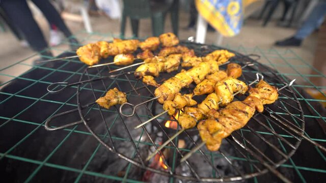 Carne variada sobre barbacoa en el exterior con amigos de fondo