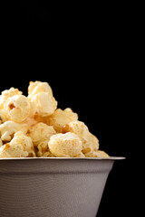 Caramel popcorn in a biodegradable bowl on black background