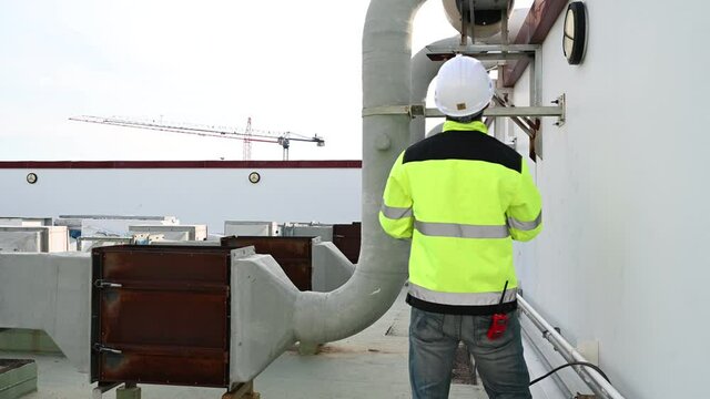 Air conditioning technicians repair and maintain condensing units outside the building, engineers inspect the operation of ventilation fans.