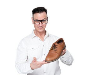 Smiling positive businessman in a white shirt and glasses holds a shoe in his hands showing the buyer, isolated on white background