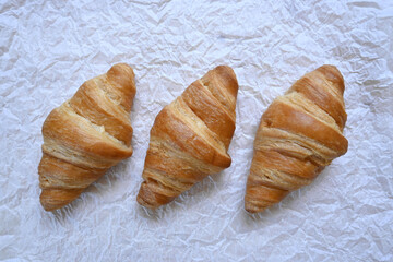 Closeup of delicious homemade golden croissants on white paper background