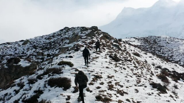 Three Persons Hiking Up to Nanga Parbat Basecamp In Pakistan - aerial drone shot