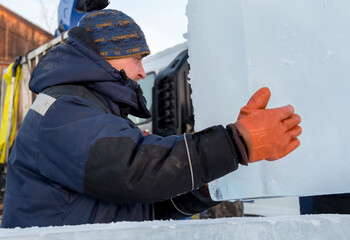 Slinger in a blue jacket unloading ice blocks