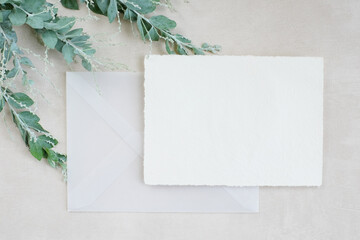 Photostock wedding styled composition. Feminine desktop mockup scene with leaves, silk ribbon, blank greeting card on white textured background. Flat lay, top view.