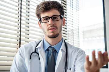 Young male doctor looking at camera explaining and talking with patient online via video calling for distance medical consulting service telehealth concepts