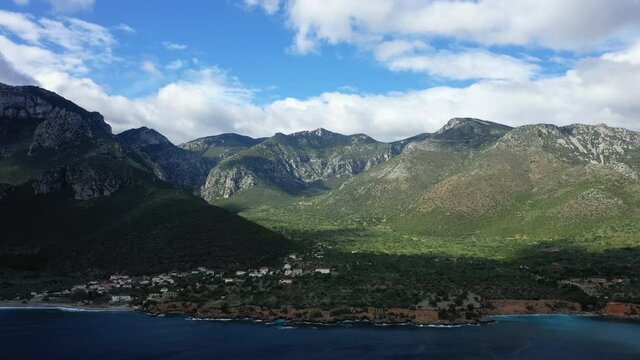 Les montagnes verdoyantes dominent les maisons d'un petit village au bord de la mer M&eacute;diterran&eacute;e vers Monemvasia, en Laconie, dans le P&eacute;loponn&egrave;se, en Gr&egrave;ce, en &eacute;t&eacute;.