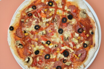 homemade pizza with olives and cheese on salmon background