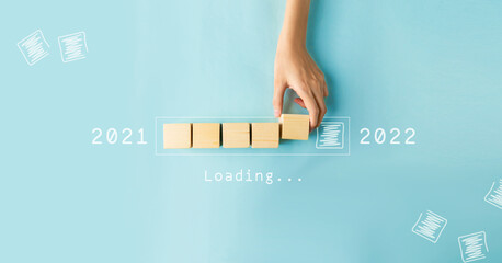 Hand of woman putting wood cube countdown to 2022. Loading year 2021 to 2022.