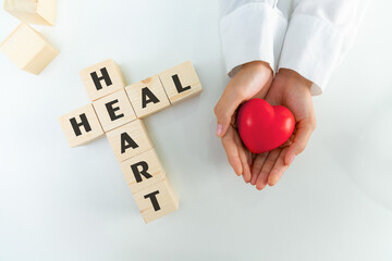 The doctor holding heart put together words from cubes HEART and HEAL. Medicine and health concept.
