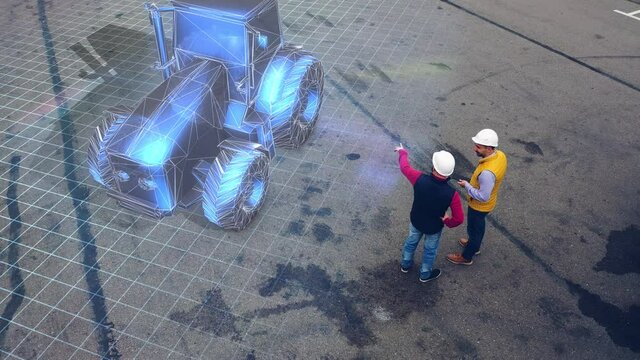 Two workers discuss a project of the new tractor using futuristic hologram equipment.