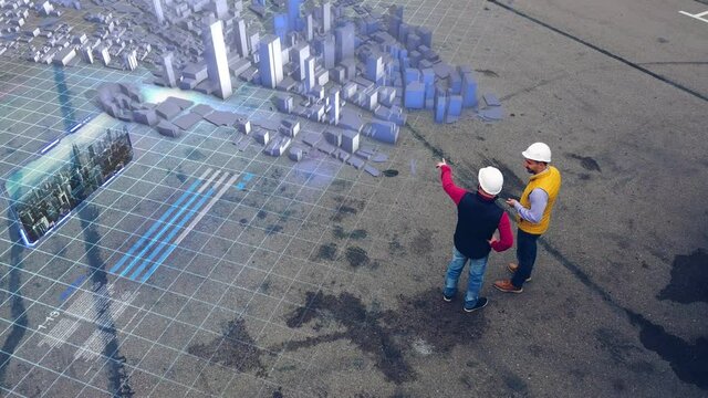 AERIAL. Two workers discussing city construction using hologram technology. Top view of the holograms city. 