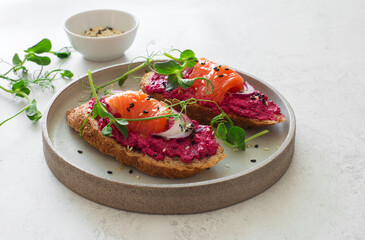Open face sandwiches with beetroot hummus, salmon, sesame seeds and micro  greens