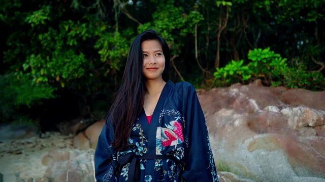 Cute Smiling Asian Girl in Kimono Laughing on a Beach at Beautiful Sunset in Slow Motion, Thailand.