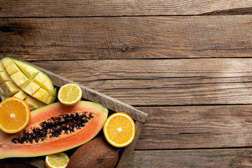 Fresh tropical fruits in a wooden box on a wooden background